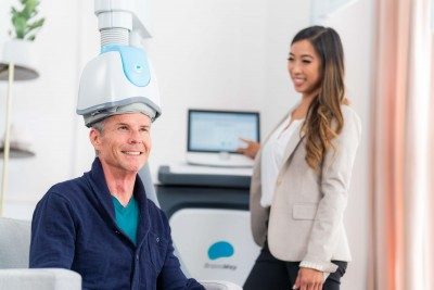 A patient receiving TMS (Transcranial Magnetic Stimulation) treatment with a clinician present