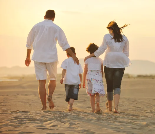 A family walking together on the beach at sunset