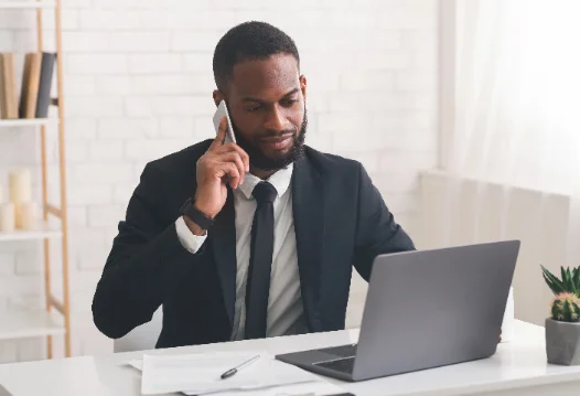 A professional on a phone call working at a laptop