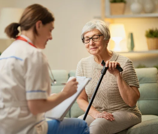 A home care nurse speaking with an older woman using a cane