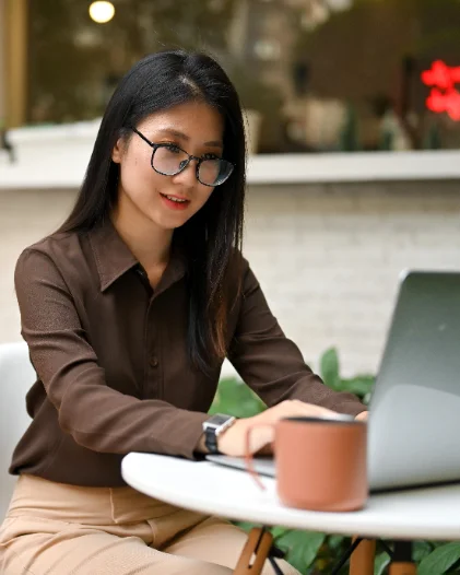 A young professional working on a laptop at an outdoor cafe table