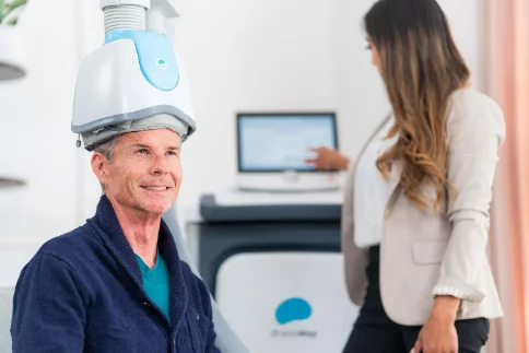A patient receiving TMS (Transcranial Magnetic Stimulation) treatment with a clinician present
